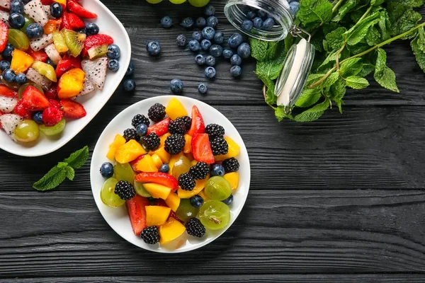 Platos con deliciosa ensalada de frutas en mesa de madera — Foto de Stock
