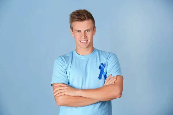 Jeune homme portant un t-shirt avec ruban bleu sur fond de couleur. Concept de sensibilisation au cancer de la prostate — Photo