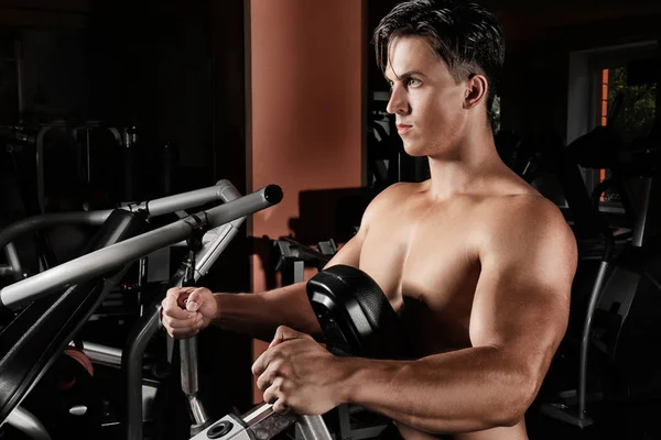 Jeune homme s'entraînant sur la machine d'exercice dans la salle de gym — Photo
