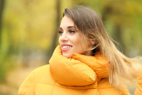 Mulher sorridente atraente em jaqueta de puffer laranja ao ar livre — Fotografia de Stock