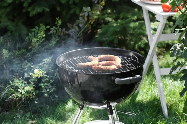 Barbecue grill with tasty sausages on backyard — Stock Photo, Image