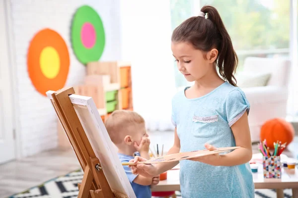 Маленькая девочка рисует дома на холсте — стоковое фото