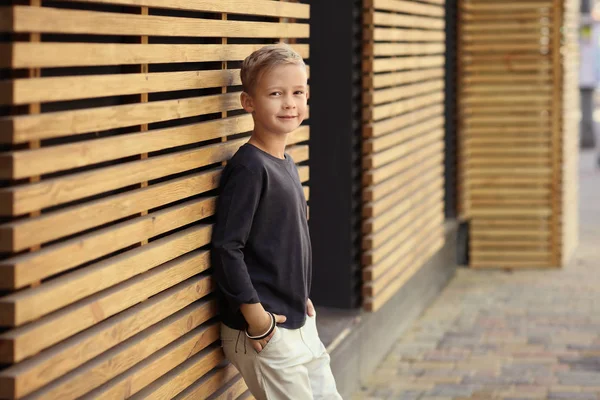 Aranyos divatos fiú szabadban a fából készült fal közelében — Stock Fotó
