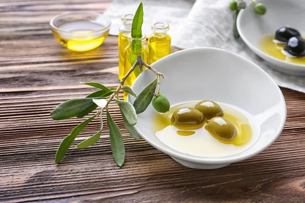 Cuenco con aceite de oliva sobre mesa de madera — Foto de Stock