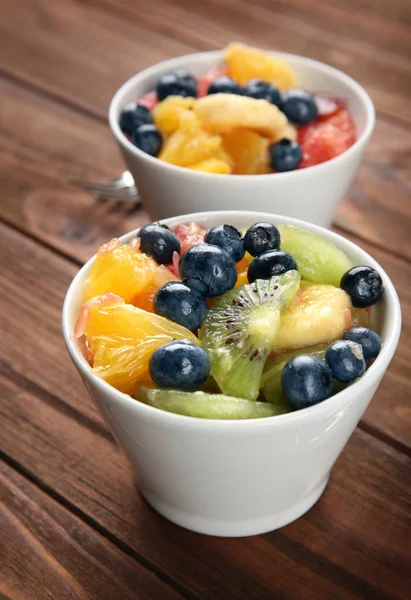 Bowls with delicious fruit salad on wooden table — Stock Photo, Image