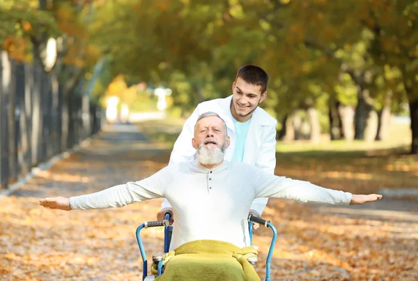 Młody opiekun spaceru z starszy mężczyzna w parku — Zdjęcie stockowe