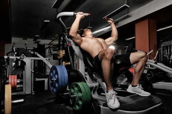 Hombre joven entrenando en una máquina de ejercicios en gimnasio —  Fotos de Stock