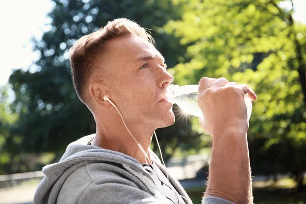 Olgun sportif adam açık havada soğuk su içme