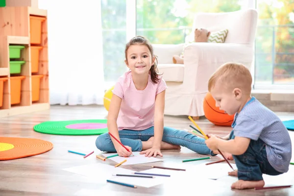 Kleine jongen en meisje puttend uit vloer thuis — Stockfoto