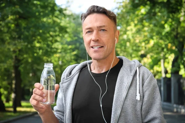 Mature sporty man with bottle of cool water outdoors