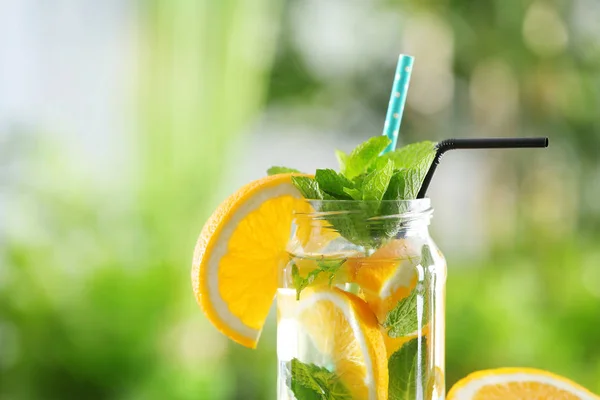 Mason jar of infused water with orange against blurred background — Stock Photo, Image