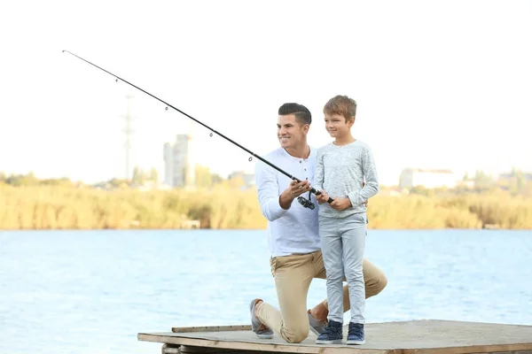 Padre y su hijo pescando desde el muelle en el río — Foto de Stock