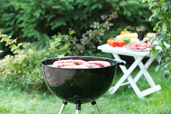 Barbecue grill avec de savoureuses saucisses sur le jardin — Photo