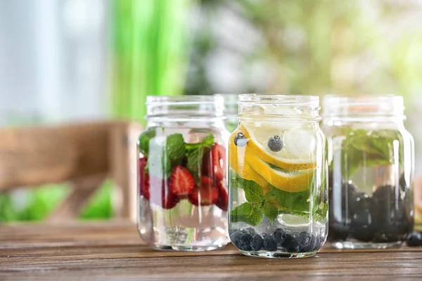 Frascos Mason de agua infundida con frutas y bayas sobre mesa de madera — Foto de Stock