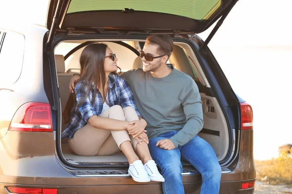 Hermosa pareja joven sentada en el maletero —  Fotos de Stock