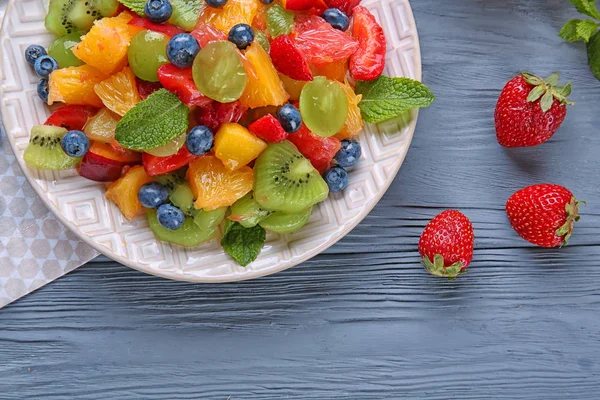 Prato com deliciosa salada de frutas na mesa de madeira — Fotografia de Stock