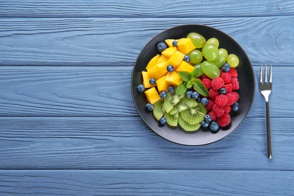 Plattan med läcker fruktsallad på träbord — Stockfoto