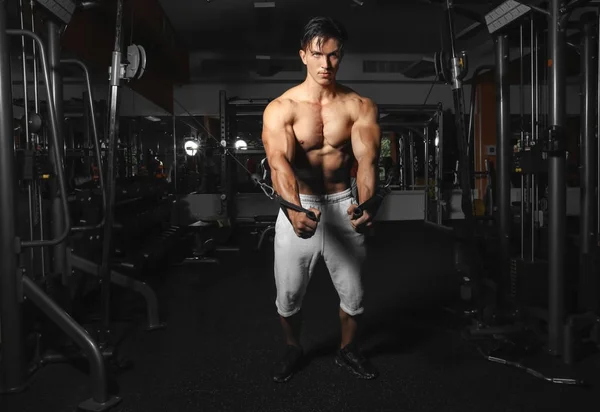 Jovem treinando em máquina de exercícios no ginásio — Fotografia de Stock