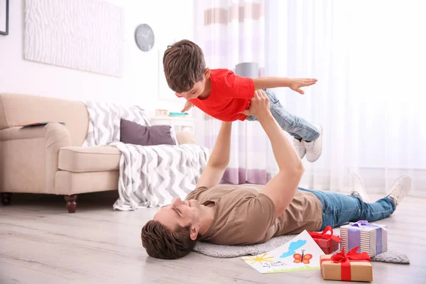 Mladý muž si hraje s jeho malým synem doma na den otců — Stock fotografie