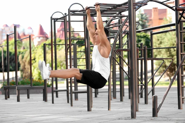 Handsome young man doing chin ups outdoors — Stock Photo, Image