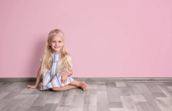 Menina bonito sentado perto da parede de cor — Fotografia de Stock