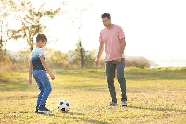 Отец и его сын играют в футбол в деревне — стоковое фото