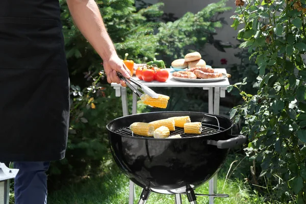 Homme préparant délicieux maïs sur barbecue grill à l'extérieur — Photo