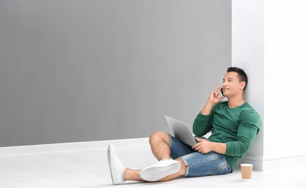 Młody mężczyzna rozmowa na telefon i za pomocą laptopa w pokoju światło — Zdjęcie stockowe