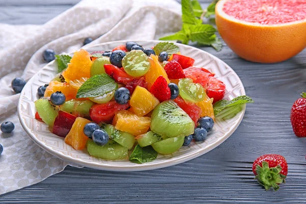 Prato com deliciosa salada de frutas na mesa de madeira — Fotografia de Stock