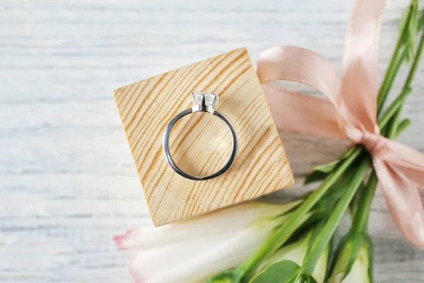 Cubo de madeira com anel de noivado de luxo no fundo claro, vista superior — Fotografia de Stock