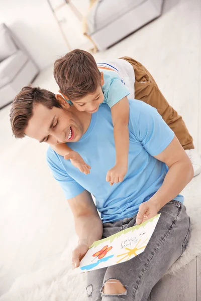 Jeune homme avec carte de voeux pour la fête des pères de son petit fils à la maison — Photo