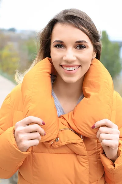 Attraktivt leende kvinna i orange puffer jacket utomhus — Stockfoto