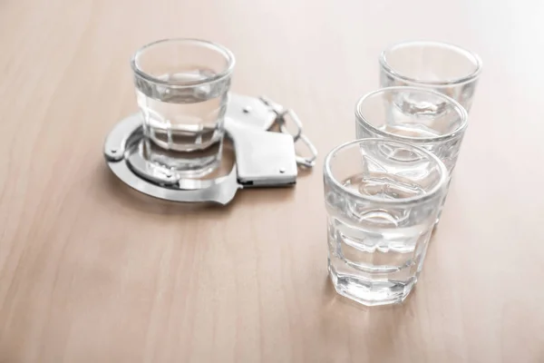 Alkol ahşap masa üzerinde kelepçe ile bardak. Alkol bağımlılığı kavramı — Stok fotoğraf