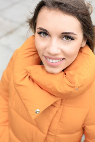 Atractiva mujer sonriente en chaqueta hinchable naranja al aire libre — Foto de Stock