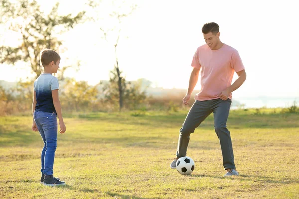 Father and his son playing soccer in countryside