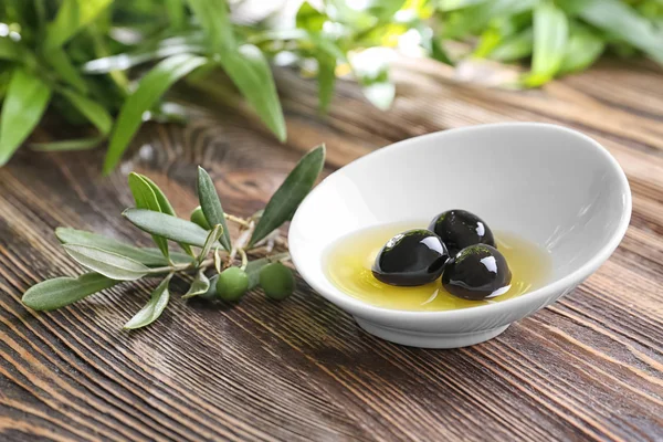 Mísa s olivovým olejem na dřevěný stůl — Stock fotografie