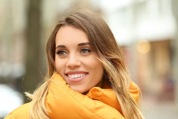 Привлекательная улыбающаяся женщина в оранжевой куртке на открытом воздухе — стоковое фото