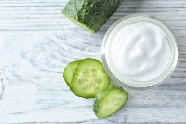 Jar with body cream and cucumber slices on wooden background — Stock Photo, Image