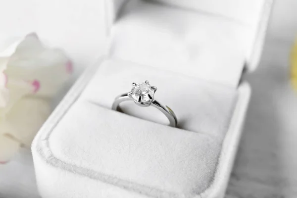 Box with luxury engagement ring on light background, closeup