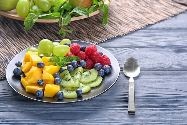 Тарілка зі смачним фруктовим салатом на дерев'яному столі — стокове фото