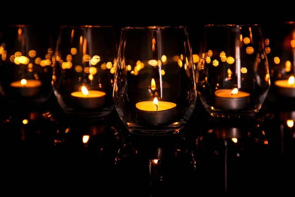 Glasses with burning candles on dark background — Stock Photo, Image