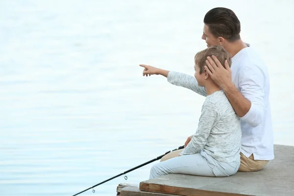 Padre y su hijo pescando desde el muelle en el río — Foto de Stock