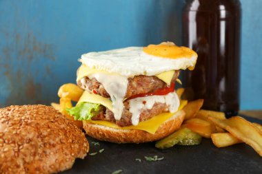 Mavi duvar karşı tablo kızarmış yumurta ile lezzetli duble burger