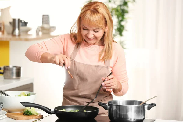 Beautiful mature woman cooking in kitchen — Stock Photo, Image