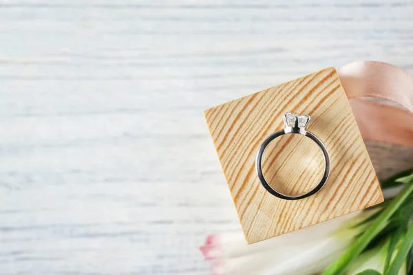 Cube en bois avec bague de fiançailles de luxe sur fond clair, vue de dessus — Photo