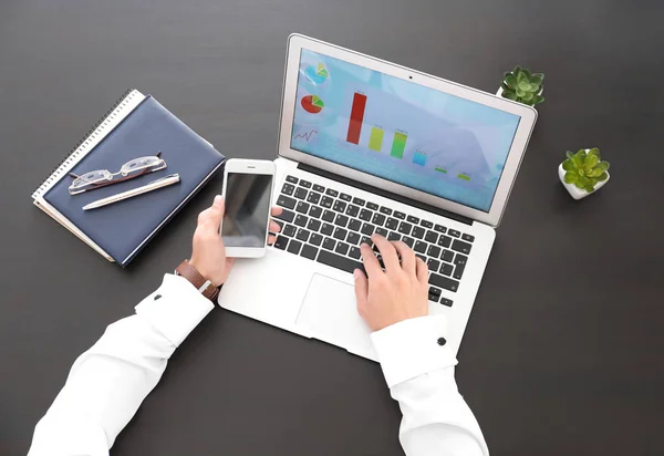 Gerente de marketing con computadora portátil y teléfono móvil en la mesa en la oficina — Foto de Stock