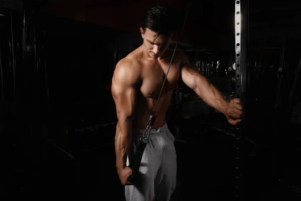 Jovem treinando em máquina de exercícios no ginásio — Fotografia de Stock