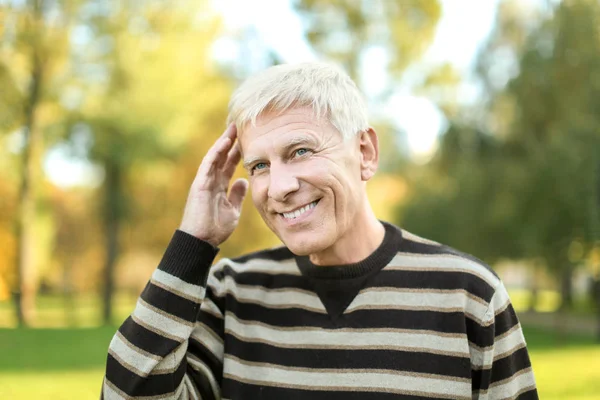 Positive mature man in autumn park — Stock Photo, Image