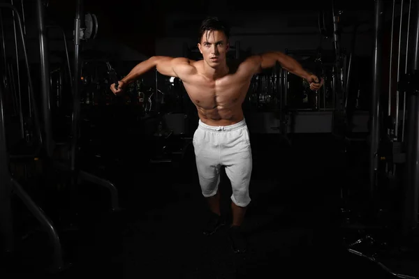 Hombre joven entrenando en una máquina de ejercicios en gimnasio —  Fotos de Stock