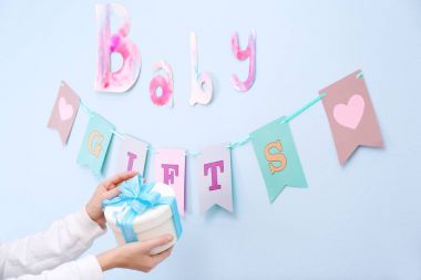 Hediye kutusu için bebek duş parti dekore edilmiş duvarının yakınında kapalı tutan kadın